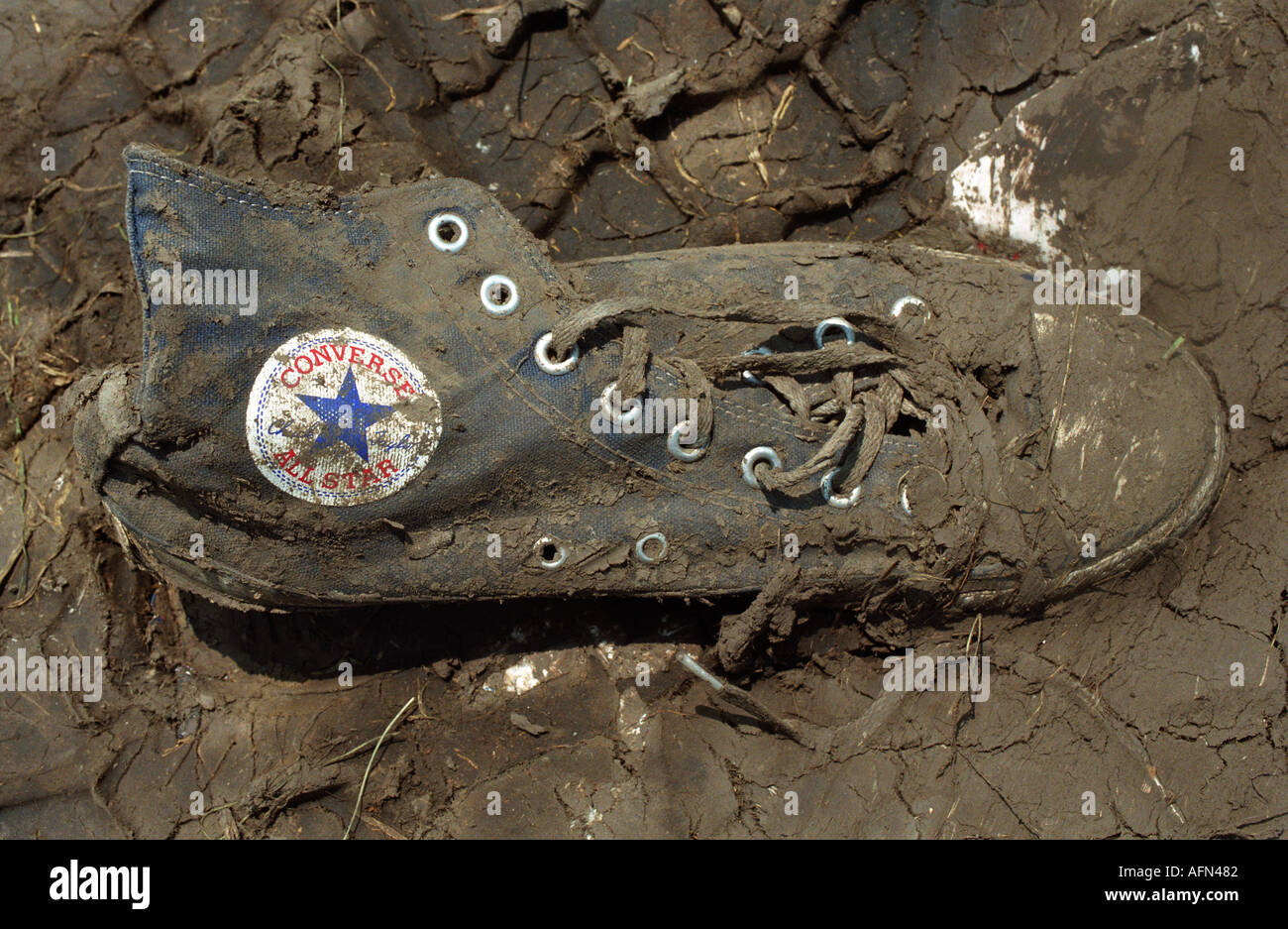 A muddy Chuck Taylor Converse lies abondoned in the mud after an outdoor  alternative music concert Stock Photo - Alamy