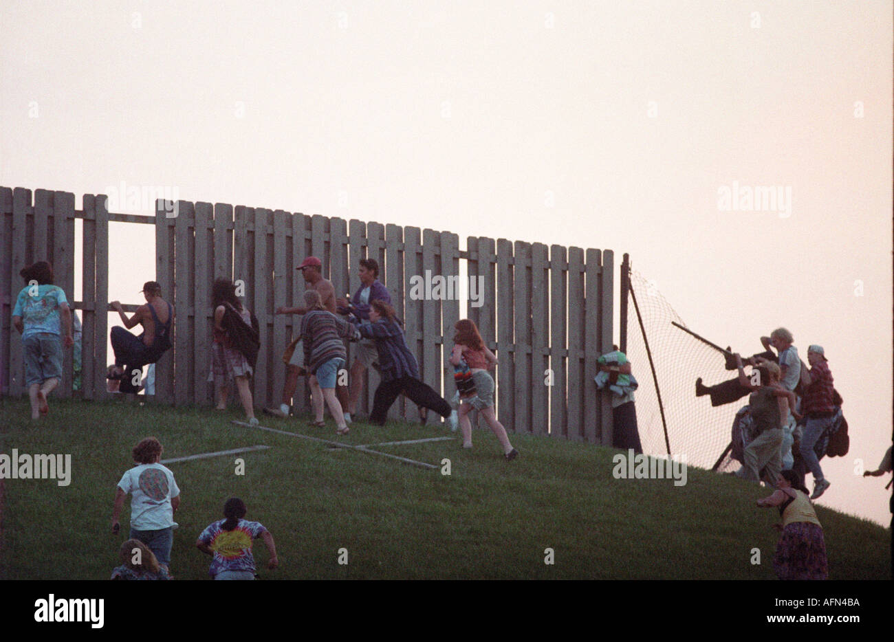 Rioting deadheads jump a fence to enter a Grateful Dead show at Deercreek Indiana during July 1995 Stock Photo