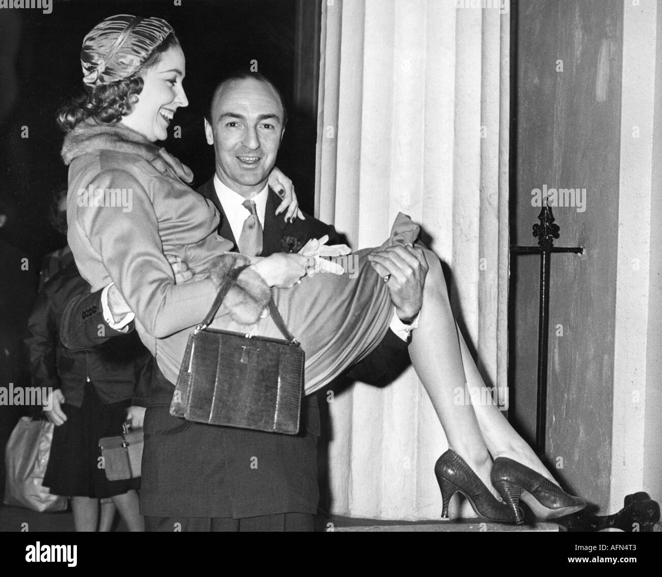 Profumo, John Dennis, 30.1.1915 - 10.3.2006, British politician, (conservative), (Tories), half length, with wife Valerie Hobson, after wedding, carrying bride over threshold, Regent's Park, London, 31.12.1954, Stock Photo