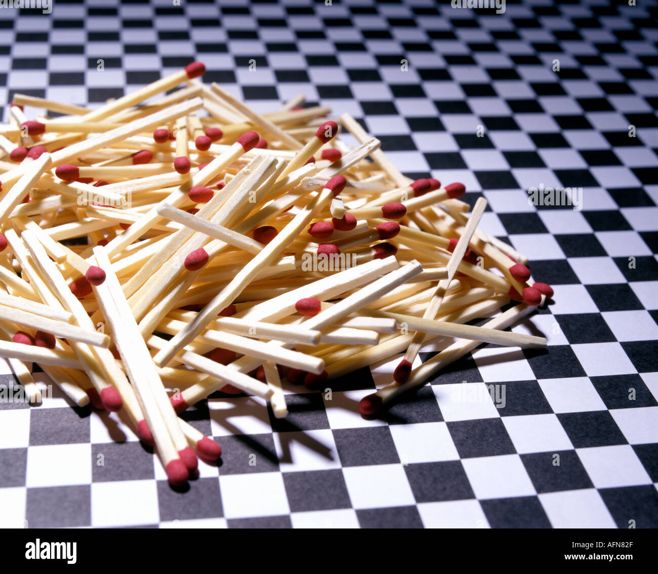Small pile of bunch of unburned matches with red striking heads on black and white checkered background surface Stock Photo
