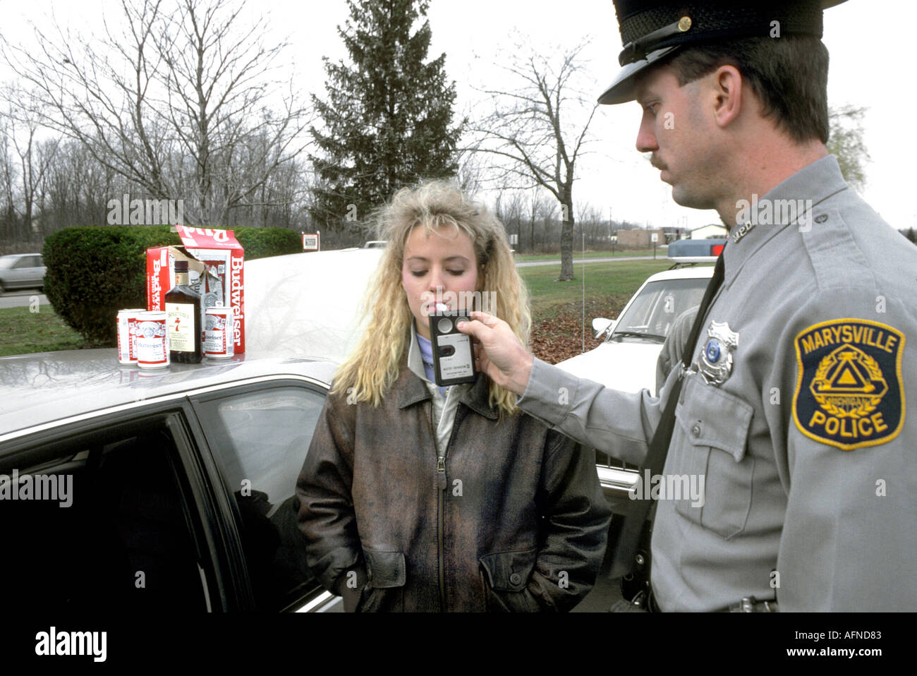 Black police officer perform a breath test on a female drunken automobile car driver Stock Photo