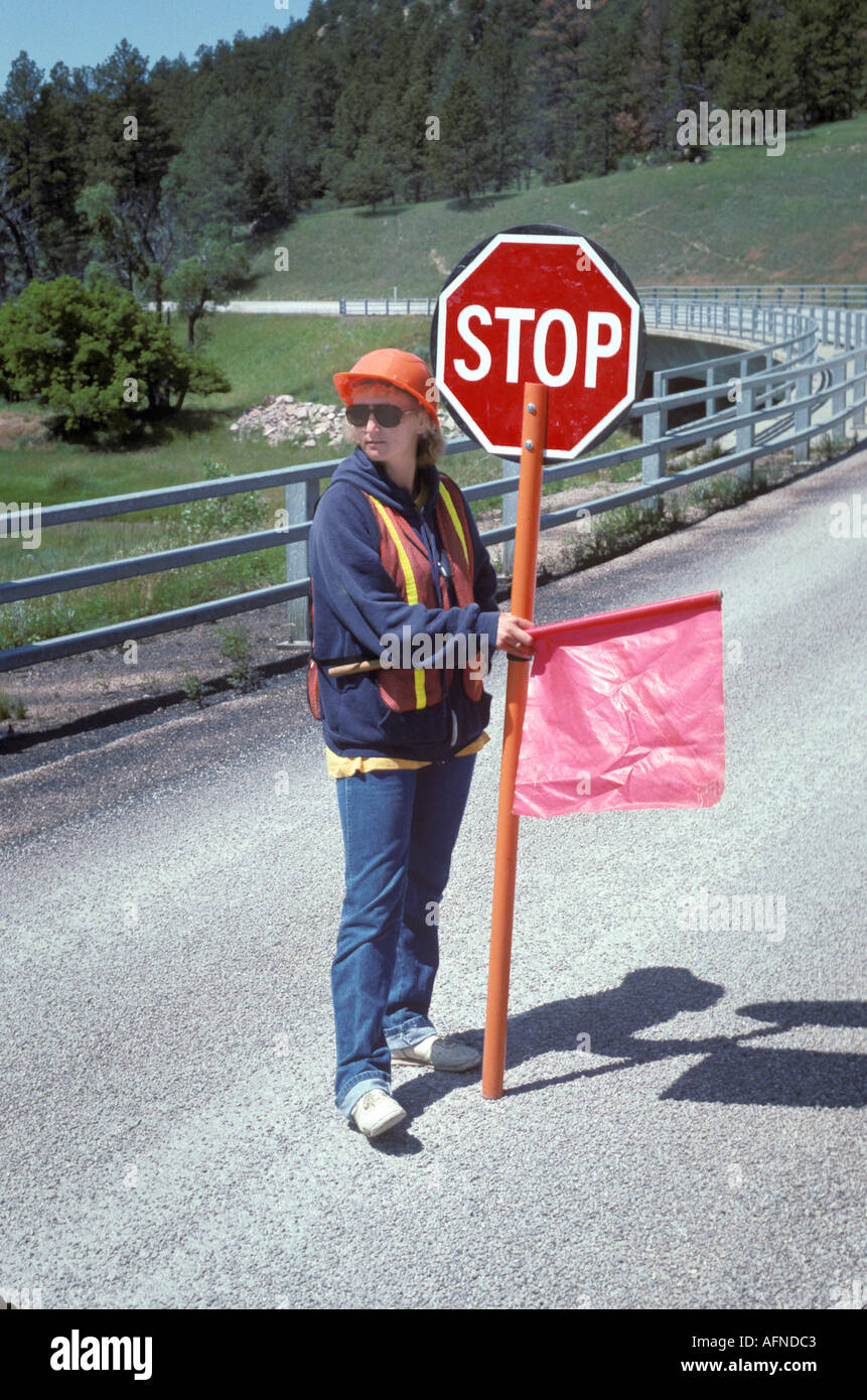 Female road guard controls traffic in a road construction area Stock