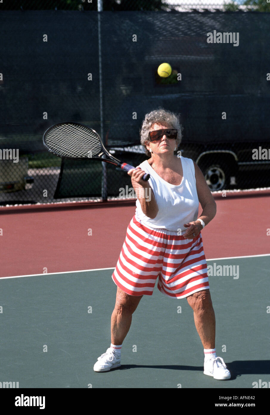 Senior female plays tennis for recreation and exercise Stock Photo