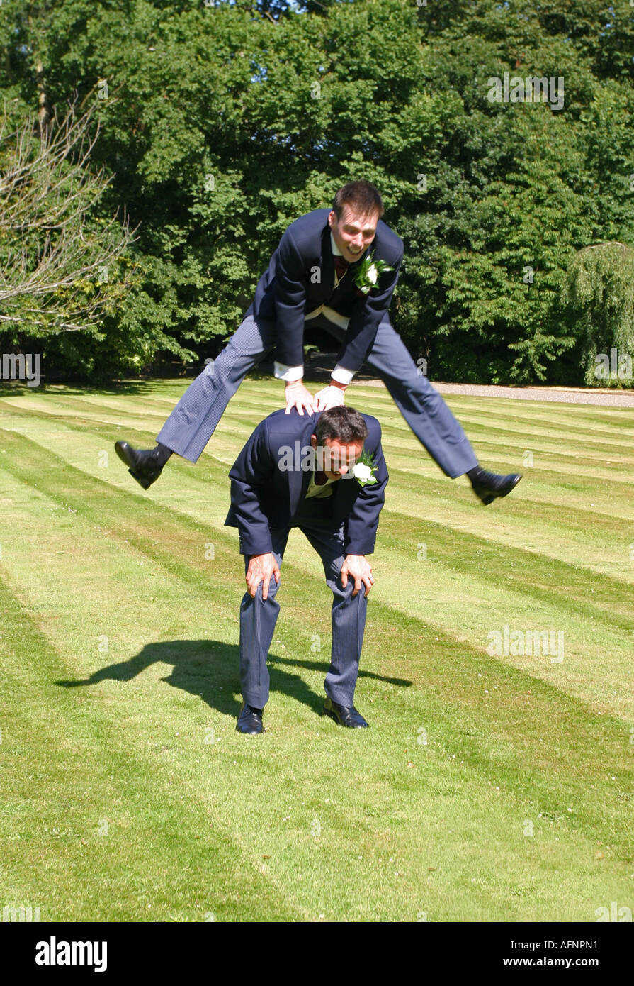 Groom playing leapfrog with best man Stock Photo