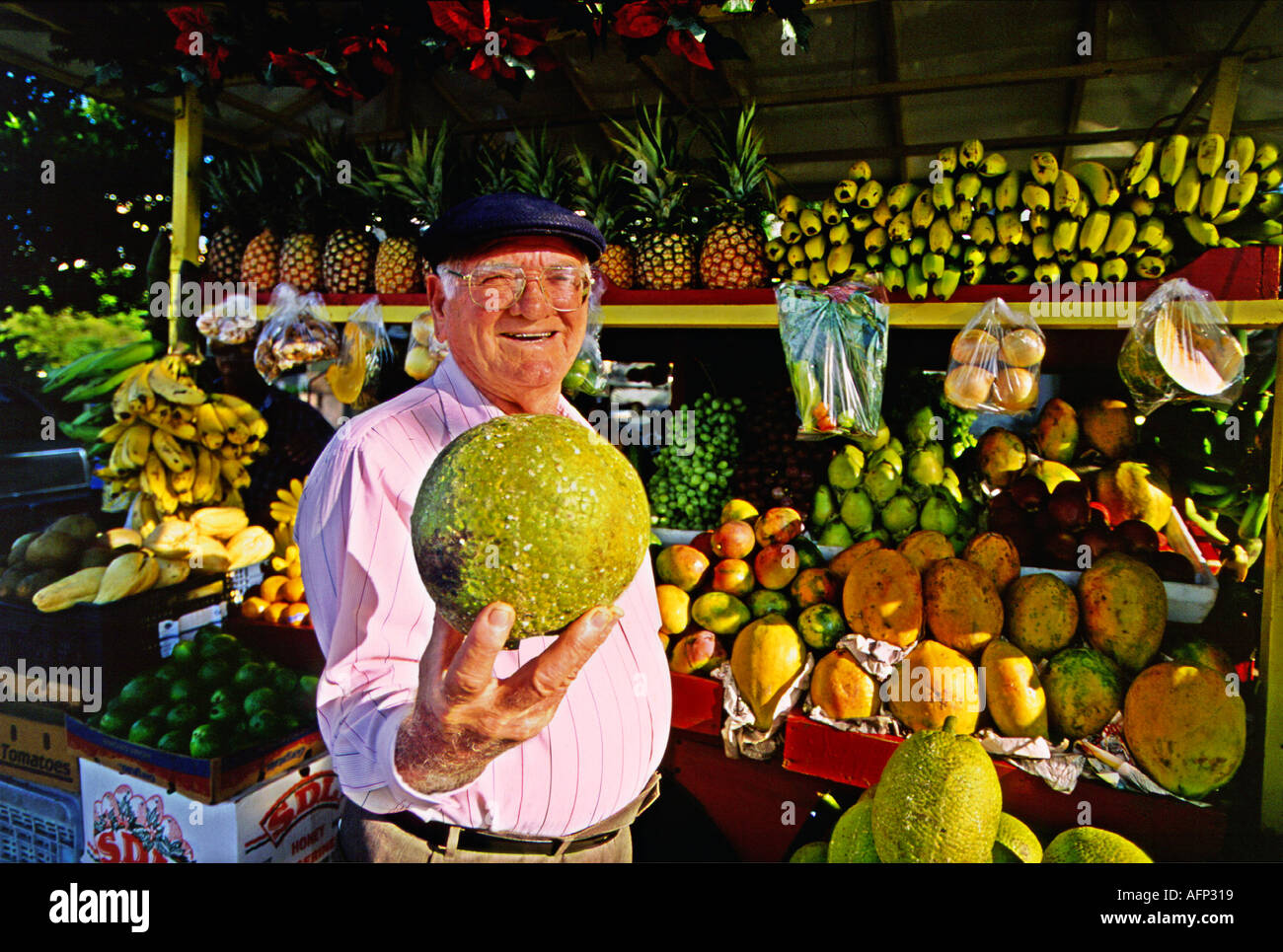 USA Old San Juan Puerto Rico Smiling mature fruit vender on street corner selling colorful produce to people Stock Photo