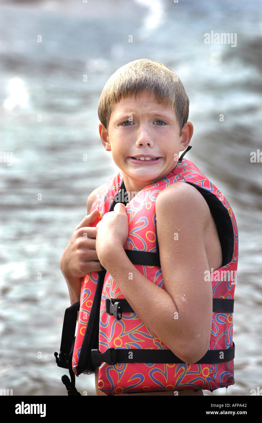 Wet 10 year old Boy in life jacket in cold of lake in fall in southern