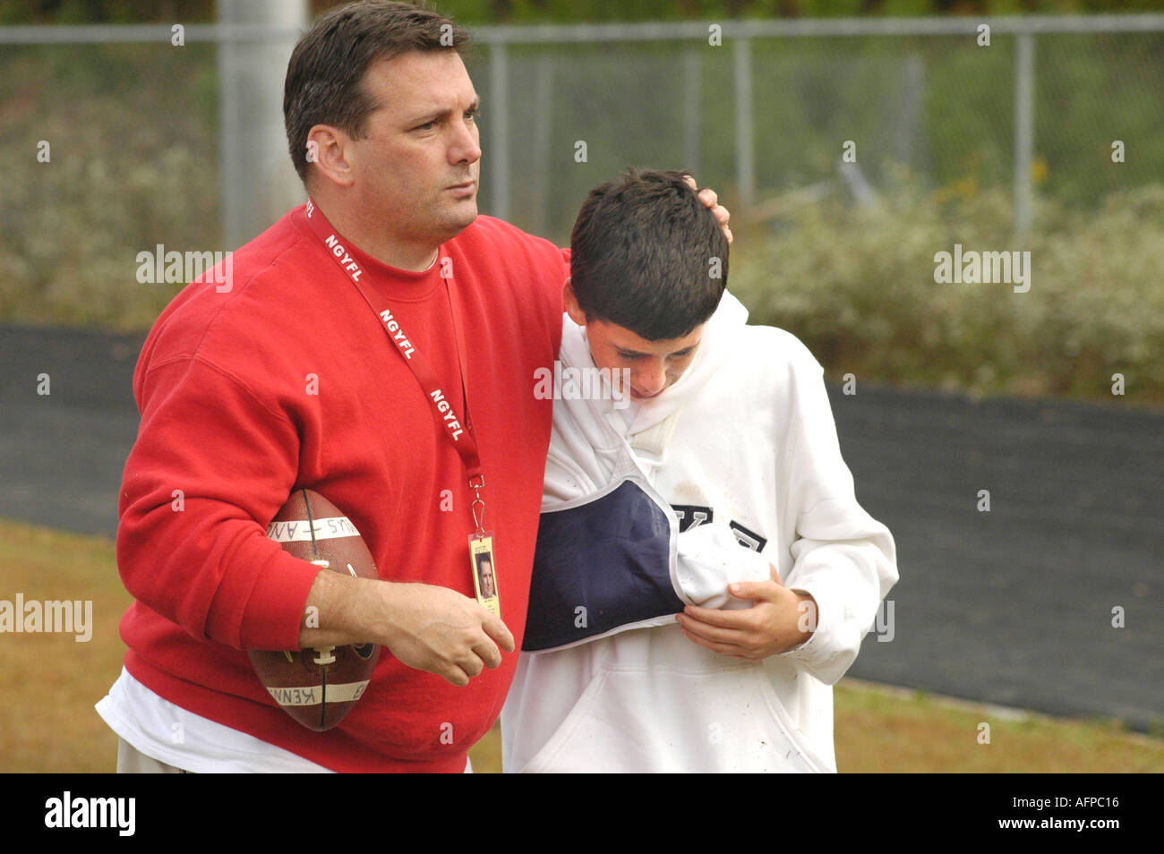 Injured young football player on bench with arm in cast from injury and