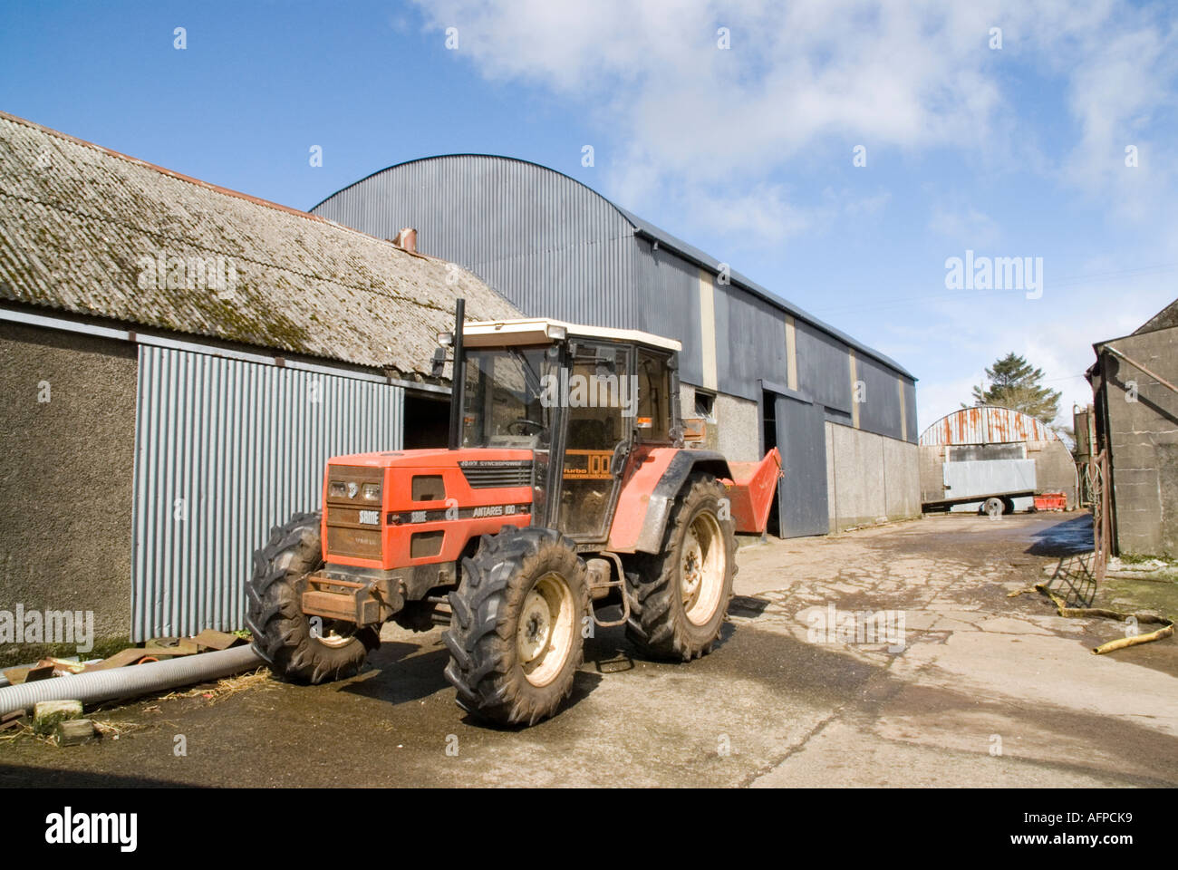 A tractor sits outside farm buildings near Glenarm Stock Photo Alamy