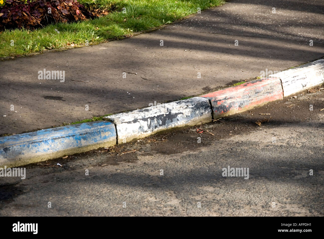 Peeling red white and blue kerb stones in Northern Ireland a fading