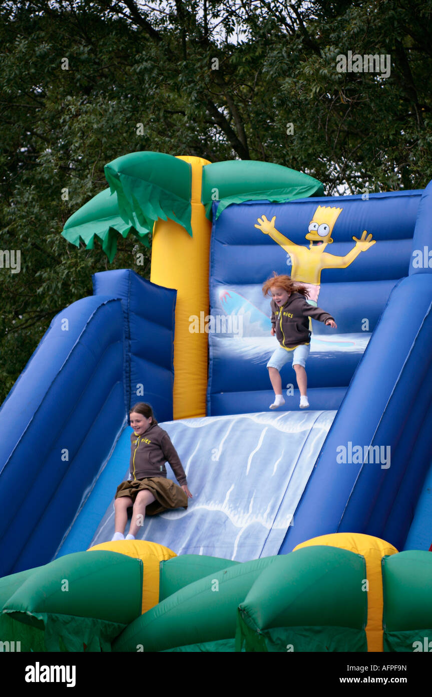 Children enjoying themselves on inflatable slide at funfair at English village fete Stock Photo