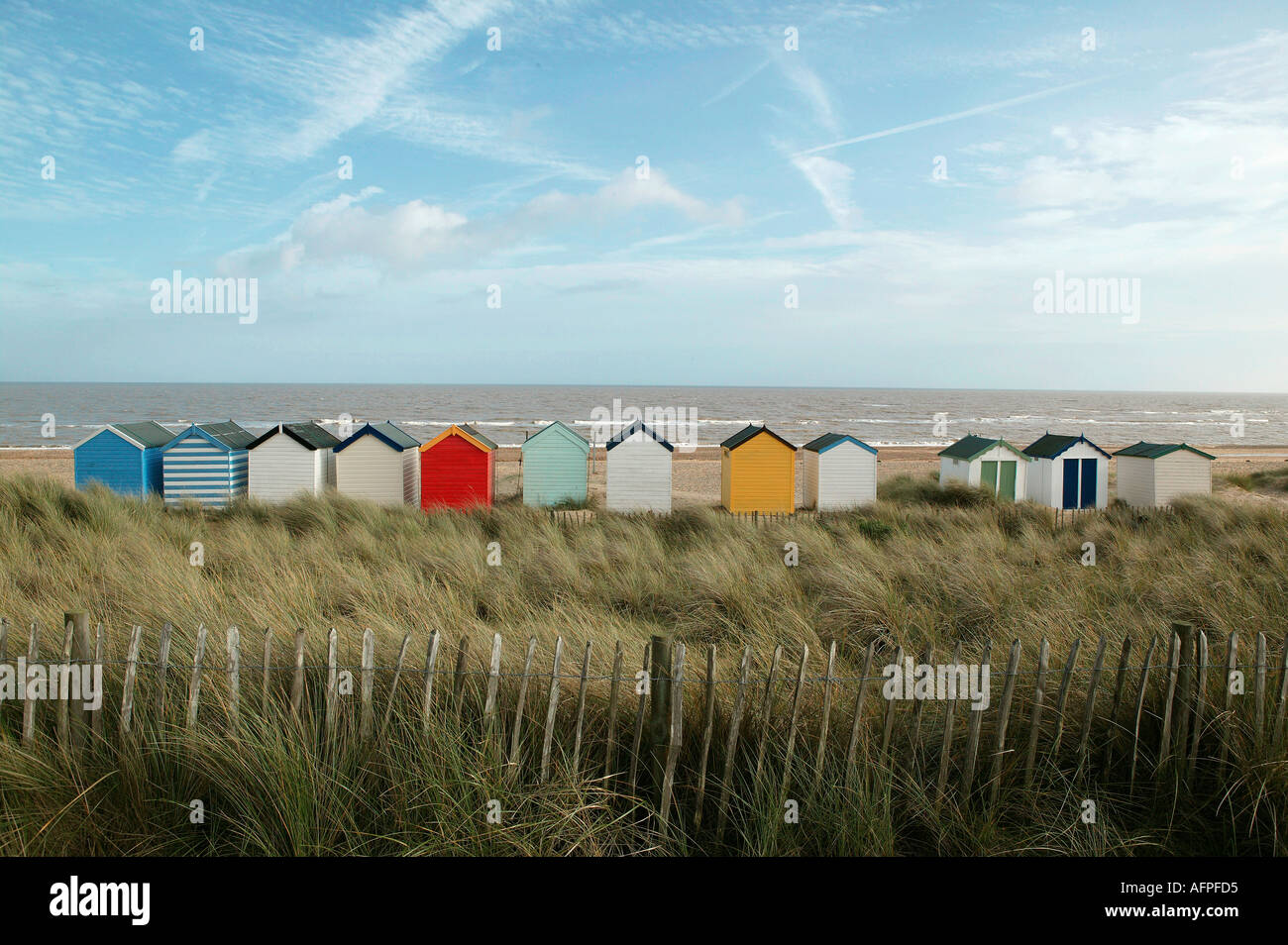Line of beach huts on a windswept english southwold coastline popular with affluent tourists including bright colors Stock Photo