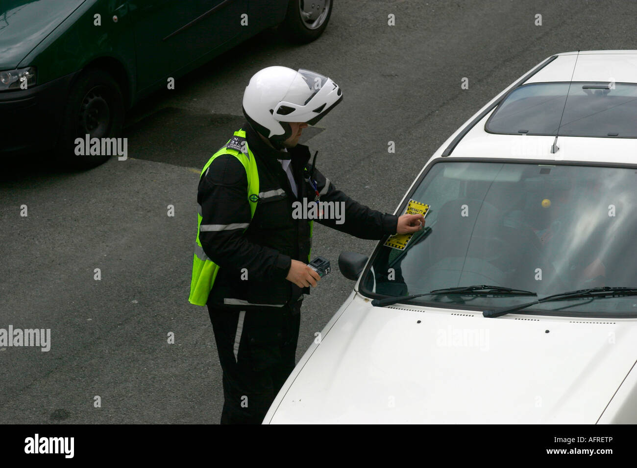 Traffic warden or parking attendant issuing a ticket to a car parked in a residential area Stock