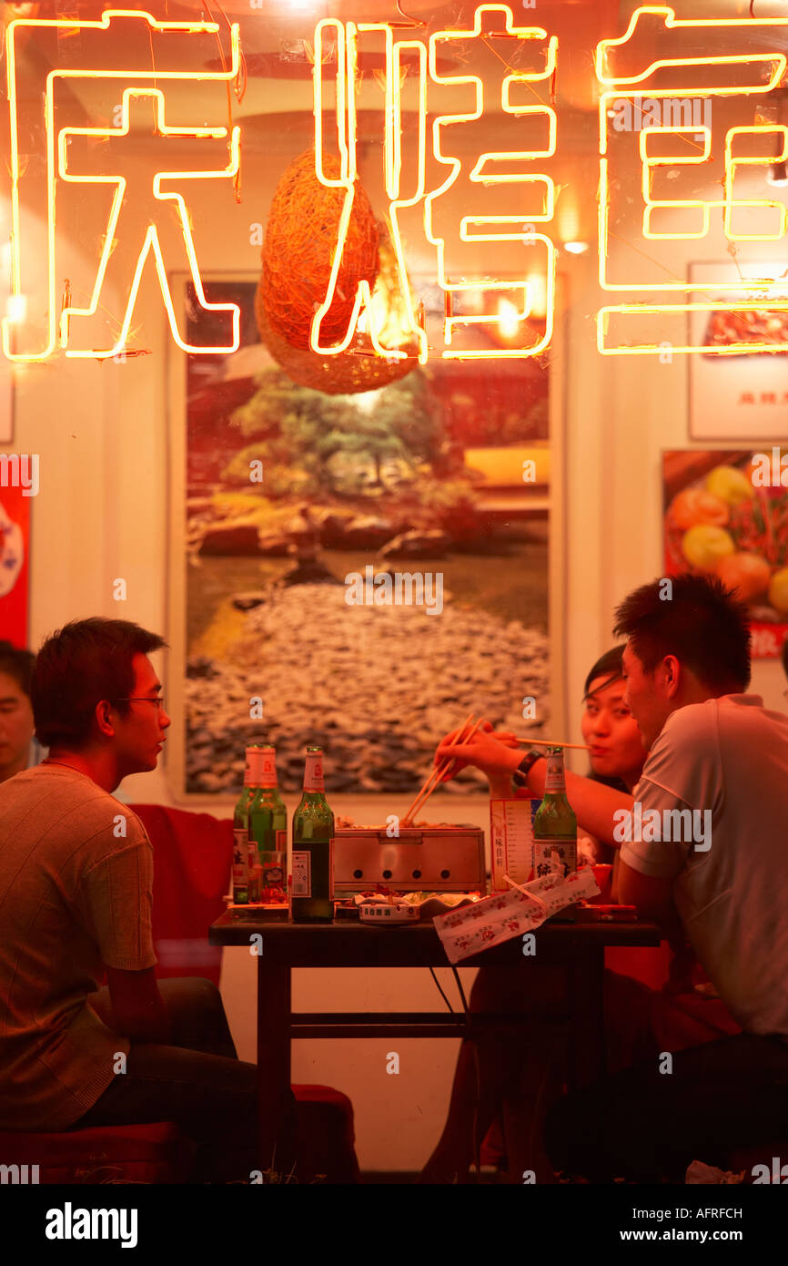 View through restaurant window of people eating, Dongzhimen Nei Dajie, Beijing, China. Stock Photo