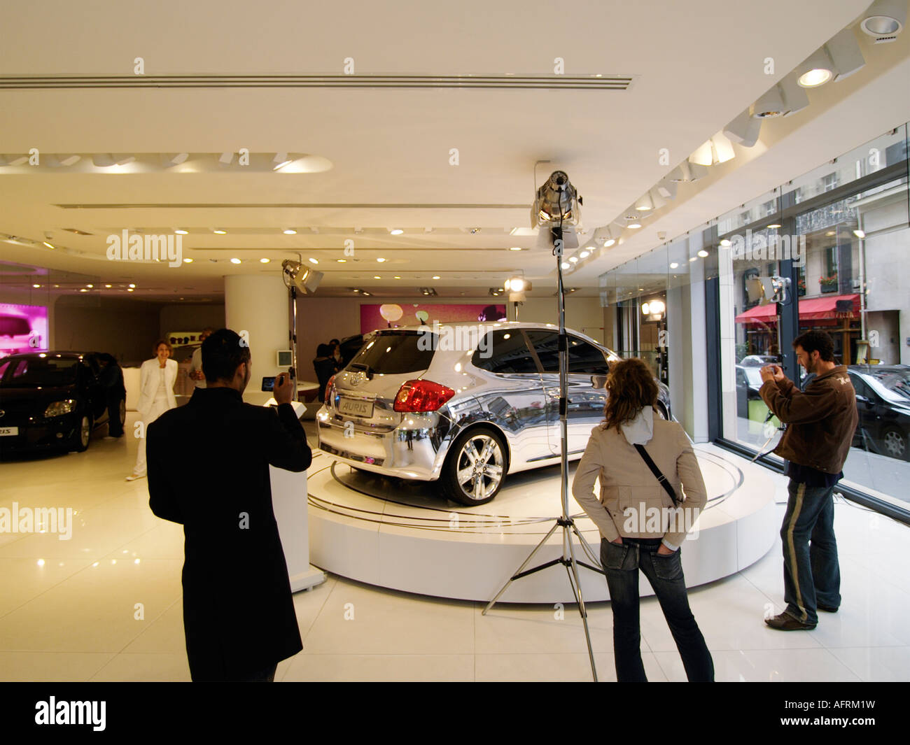 Young people taking pictures and admiring a completely chromed Toyota Auris car in the Toyota flagship showroom in Paris France Stock Photo