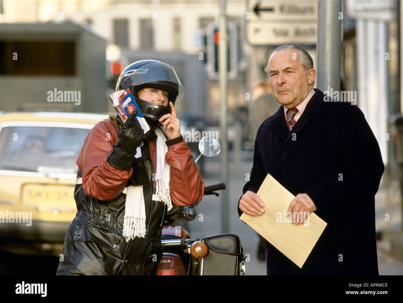 Female motorcycle courier giving directions to pedestrian1980s London