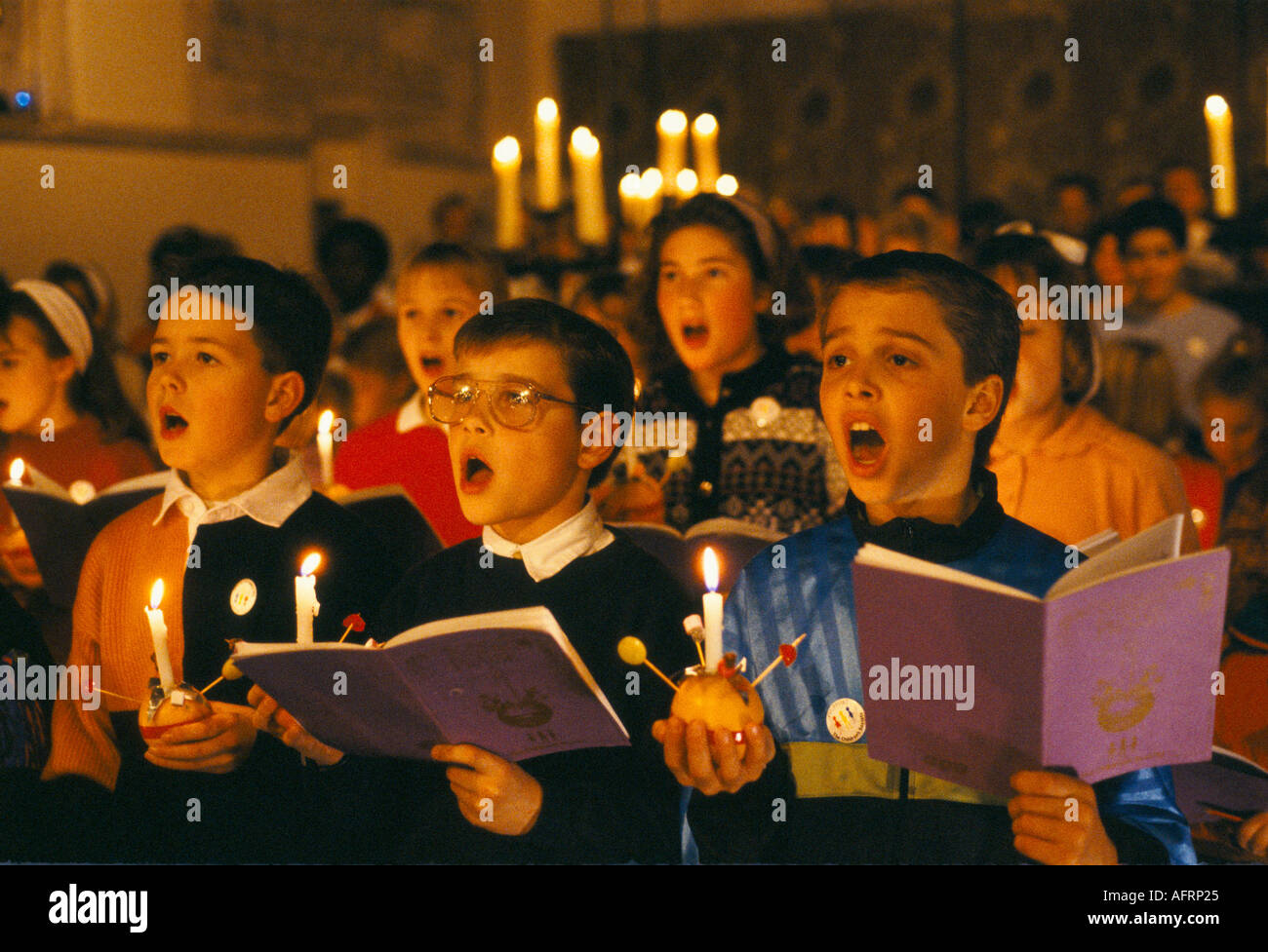 Christingle Christmas church carol service school children choir singing. Holding lit candles with orange Leighton Buzzard 1990s UK HOMER SYKES Stock Photo