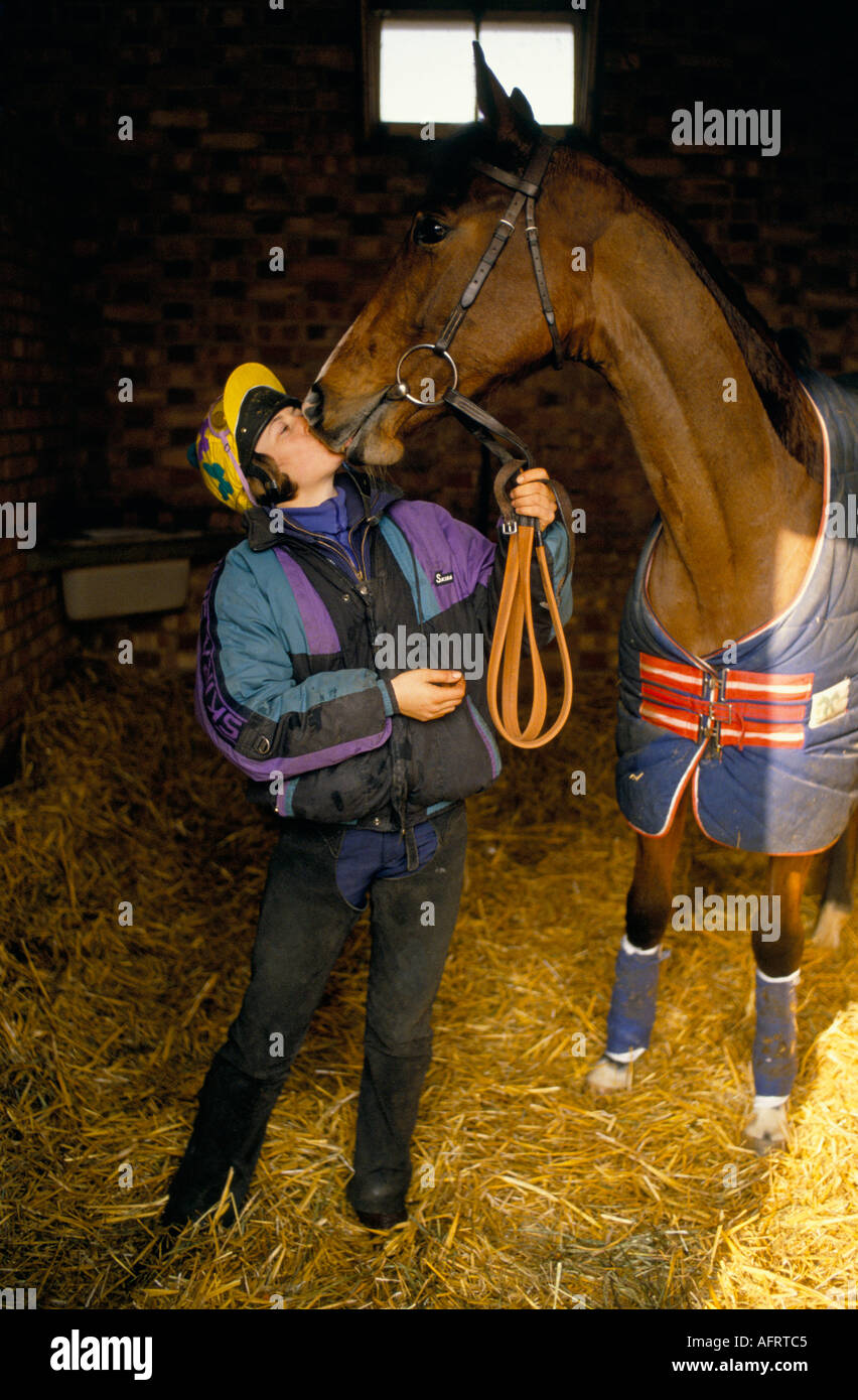 Stable girl at trainer, Sir Michael Stoute thoroughbred racehorse yard kissing Jood who she is looking after on the nose. 1990s 1993 UK HOMER SYKES. Stock Photo