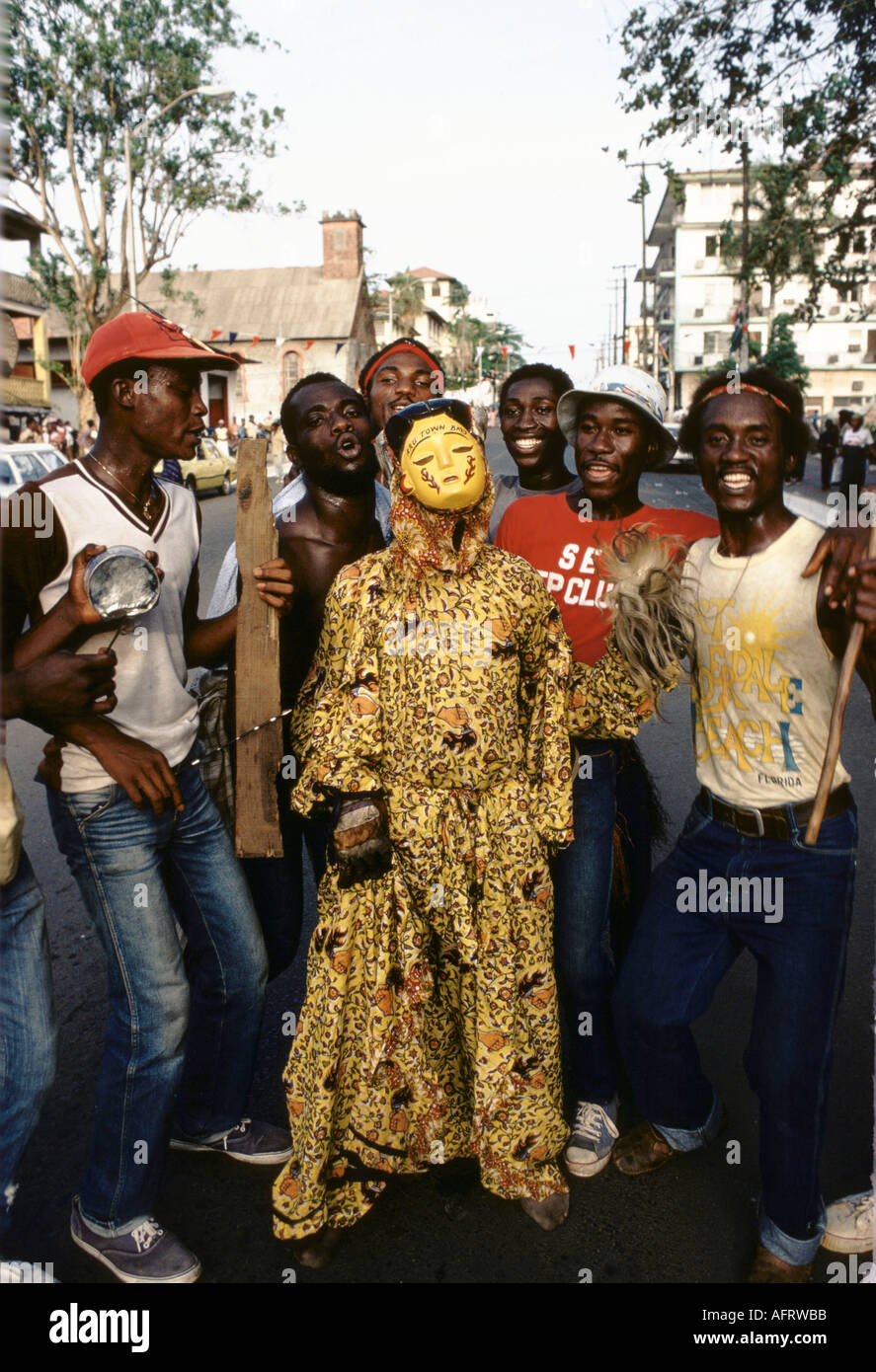 Liberia, Monrovia, National Redemption Day celebrations annually on 12th April. Group of men with costumed figure West Africa. 1983 1980s HOMER SYKES Stock Photo