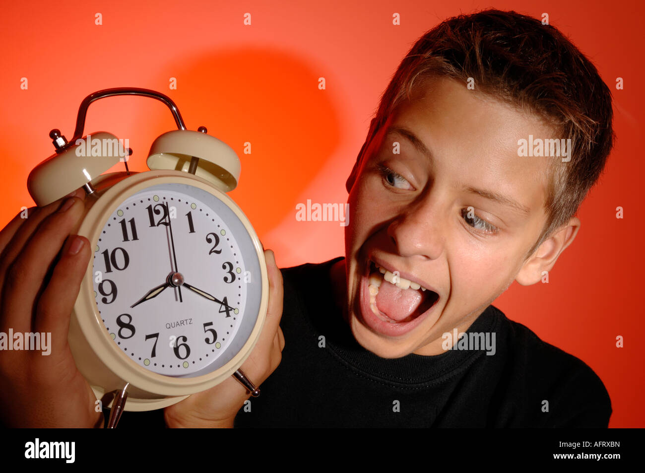Boy shouting at an alarm clock Stock Photo
