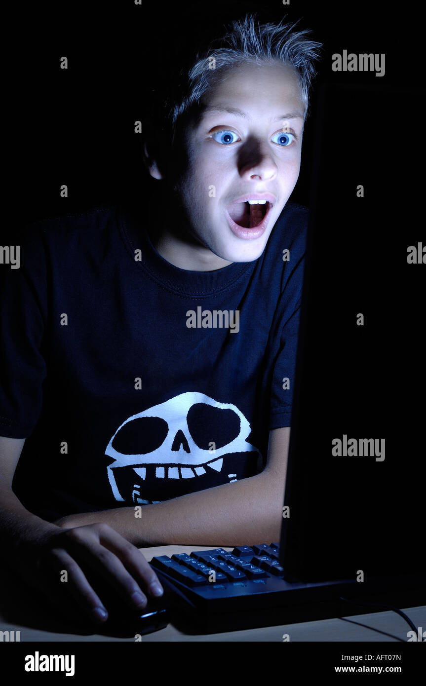 Boy looking surprised infront of a computer screen Stock Photo