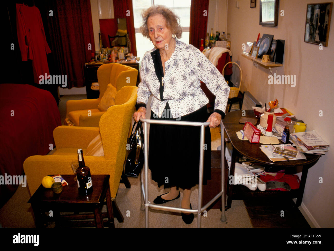 Care home Uk elderly woman Miss Dorothy Hill using Zimmer walking frame her own bed sitting room. Cirencester Gloucestershire 1990s UK 1991 Stock Photo