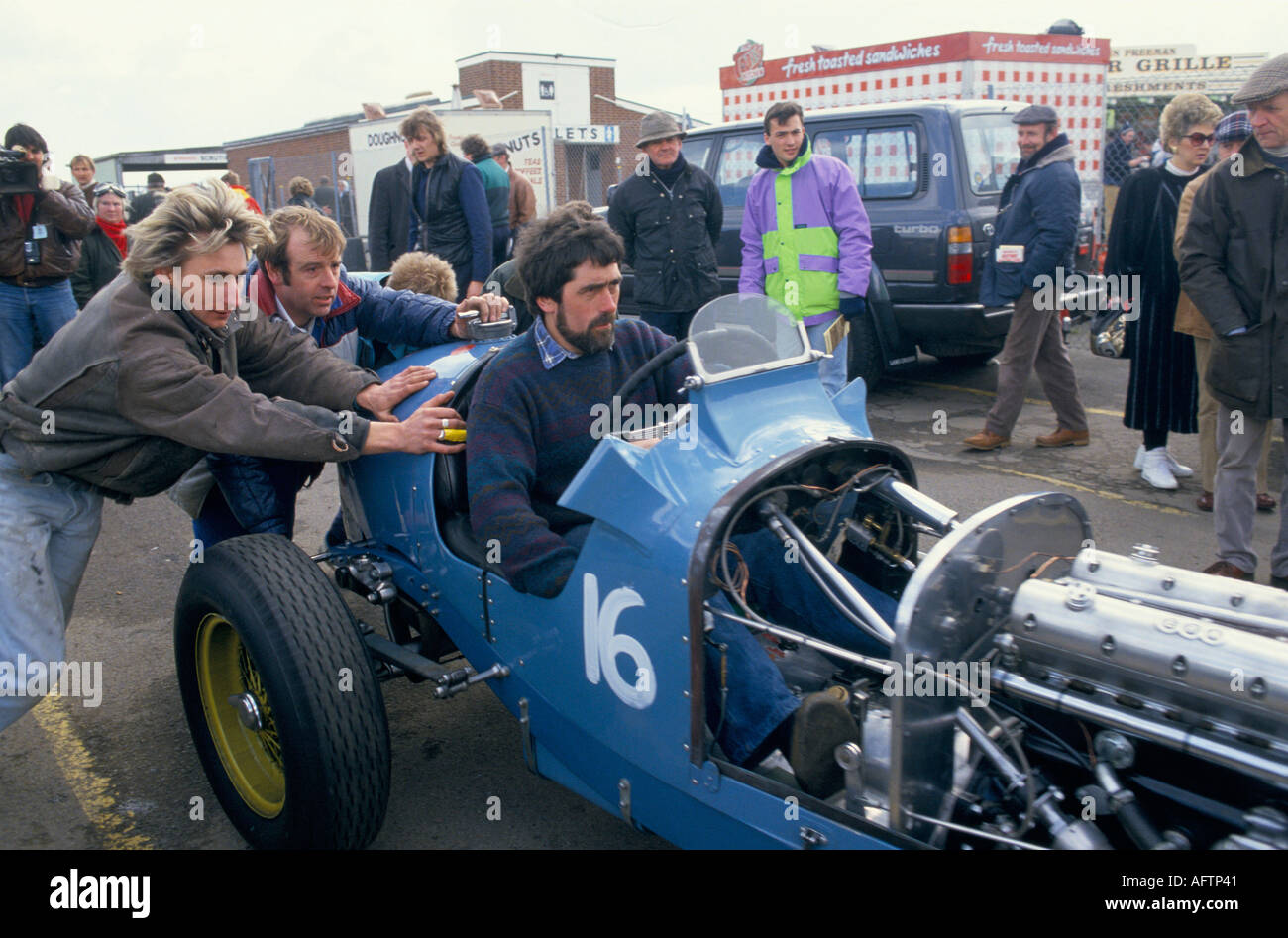 Vintage classic racing sports car enthusiasts help to push vehicle with