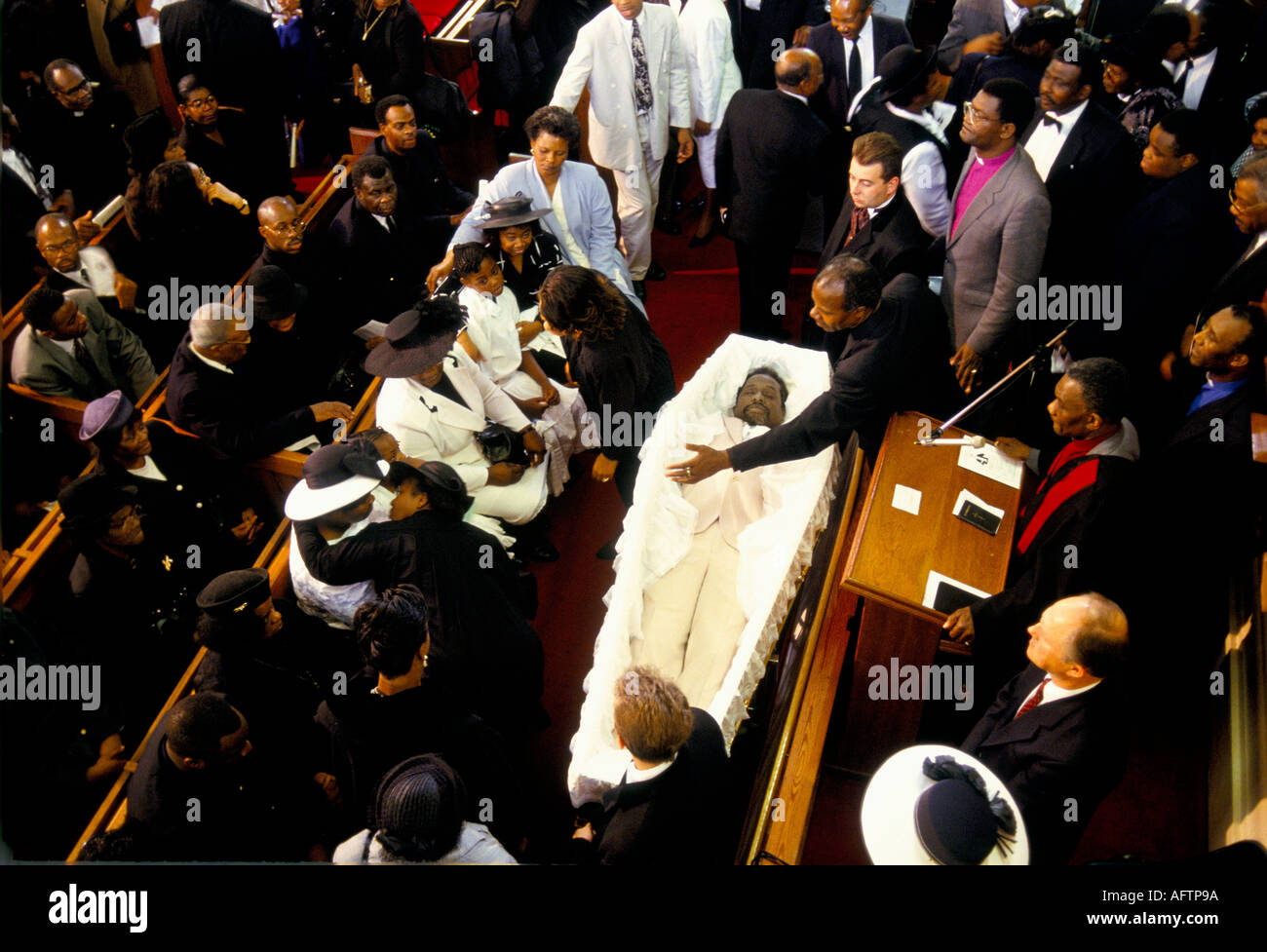 Mourners sitting in pews with corpse in open  coffin at funeral service in church New  Testament Church of God London Stock Photo