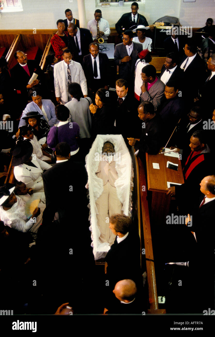 Mourners standing seated in pews with corpse in open coffin at a the New  Testament Church of God funeral service London Stock Photo