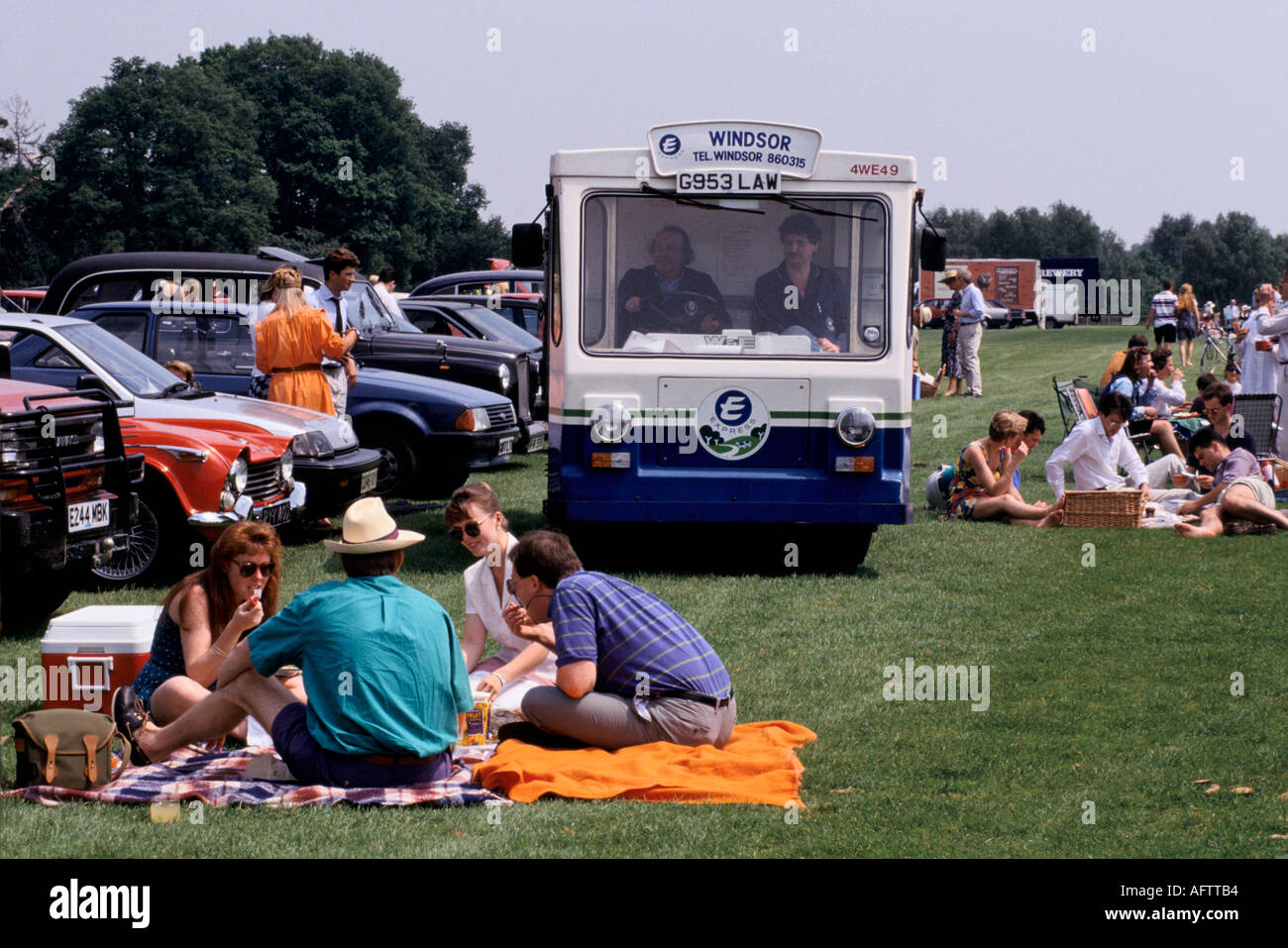 Milk van or milk float making a delivery to car park at Windsor Great Park people having picnic before the polo game starts. 1980s 80s UK HOMER SYKES Stock Photo