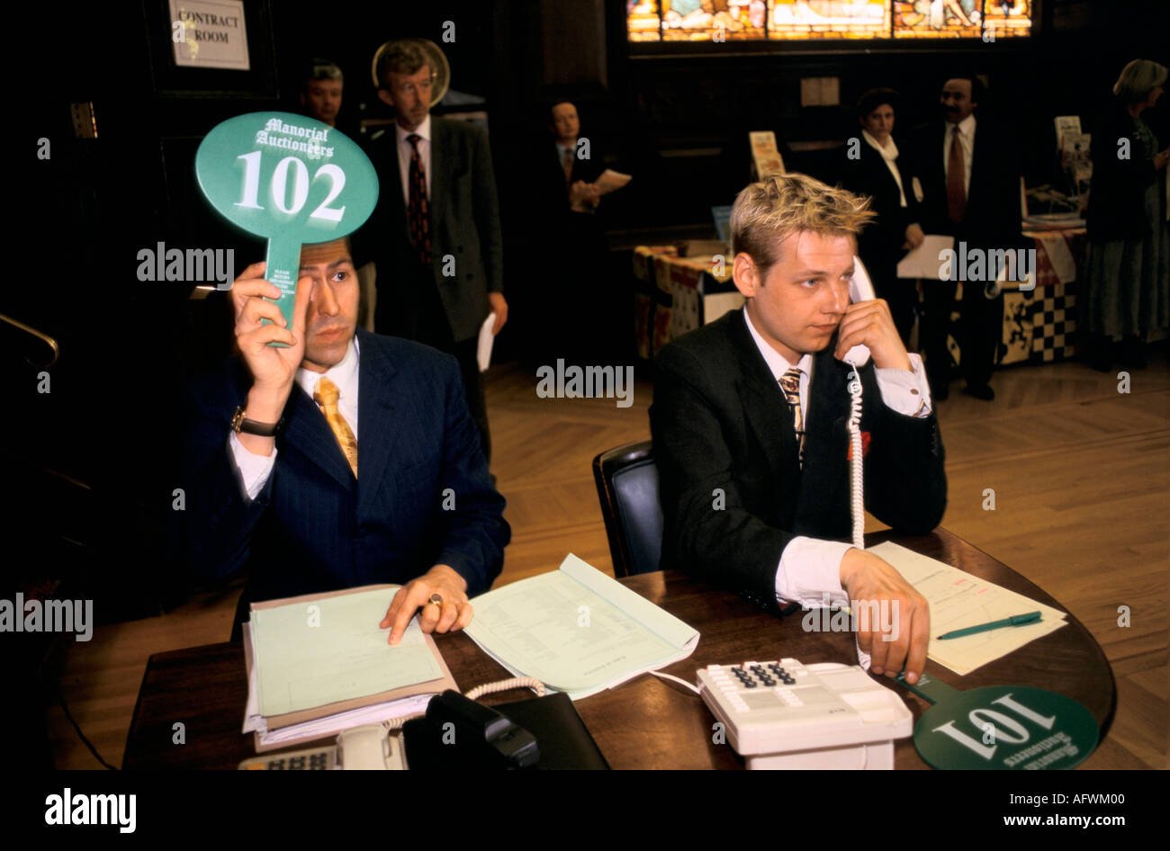Auction room 1990s man taking a telephone bid over the phone from a client holding up an auction paddle London 90s UK HOMER SYKES Stock Photo