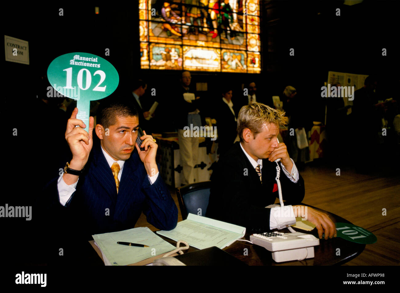 Auction room 1990s man taking a telephone bid over the phone from a client holding up an auction paddle London 90s UK HOMER SYKES Stock Photo