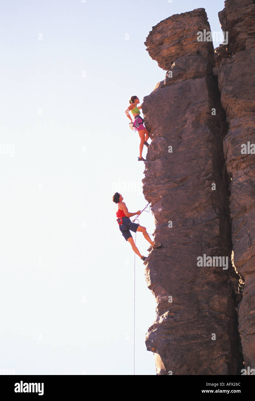 A couple climb a vertical basalt column woman leads Washington State Stock Photo