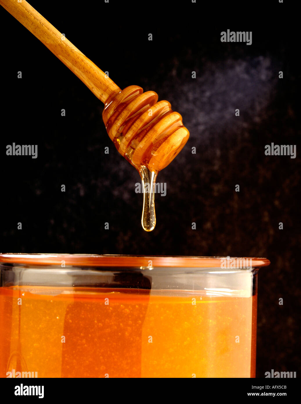 wooden honey dipper with honey and jar Stock Photo