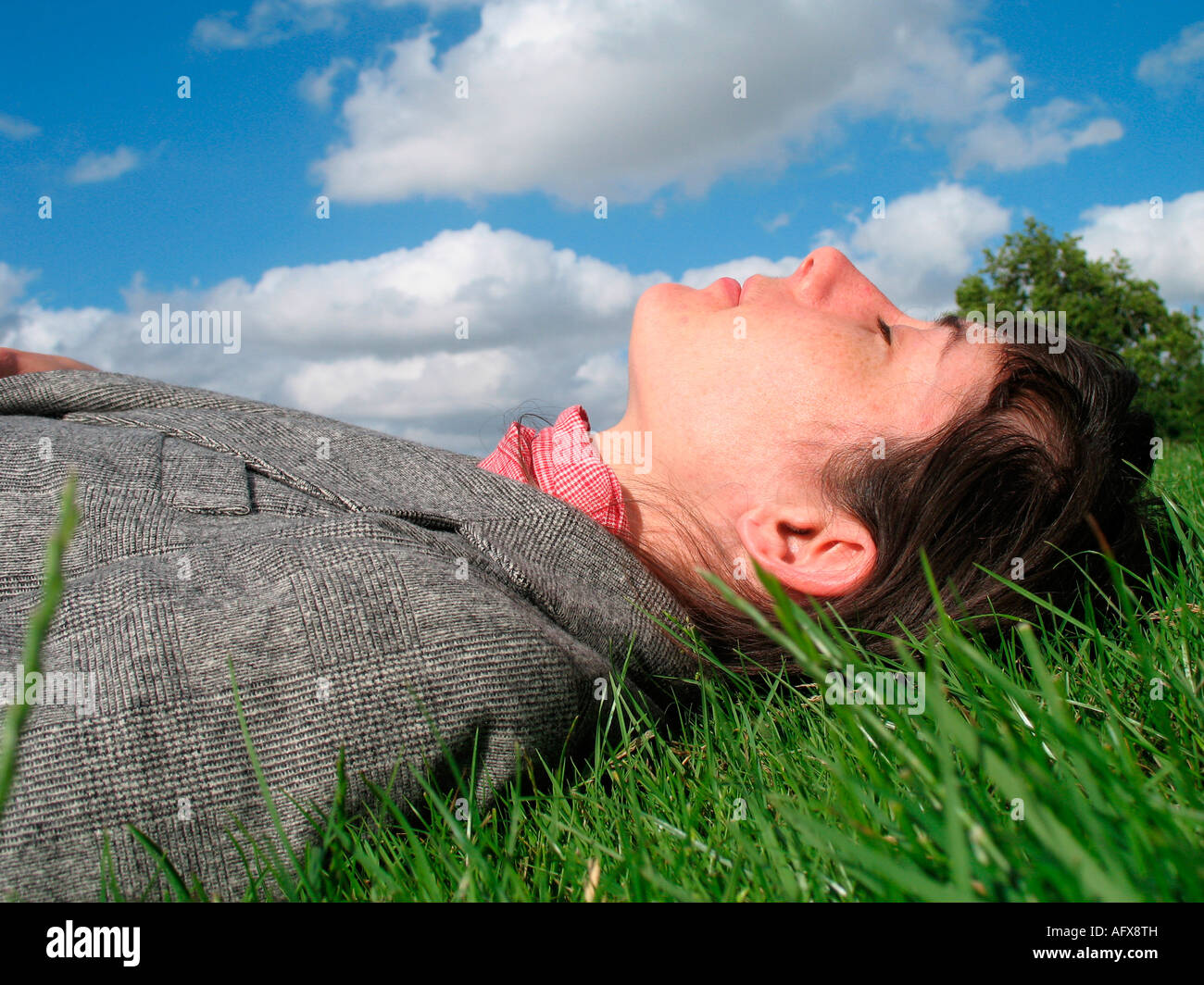 A woman lying down on the grass with blue sky Stock Photo