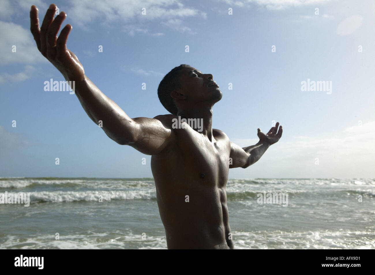 Man with arms stretched out on beach in sun Stock Photo - Alamy
