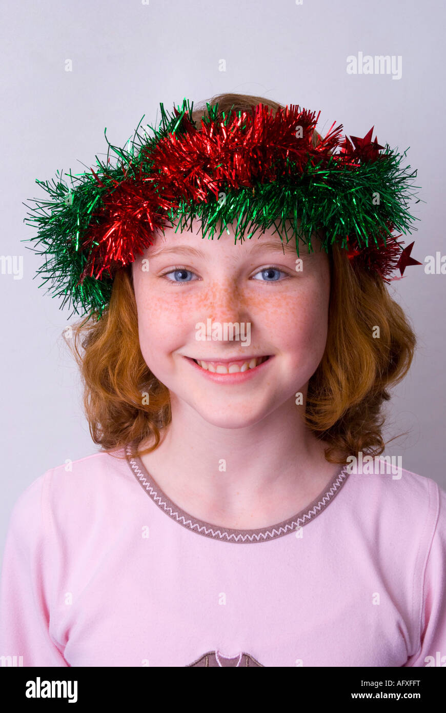 A smiling blue eyed freckle faced 11 year old girl of Irish origin wearing Christmas tinsel in her hair Stock Photo