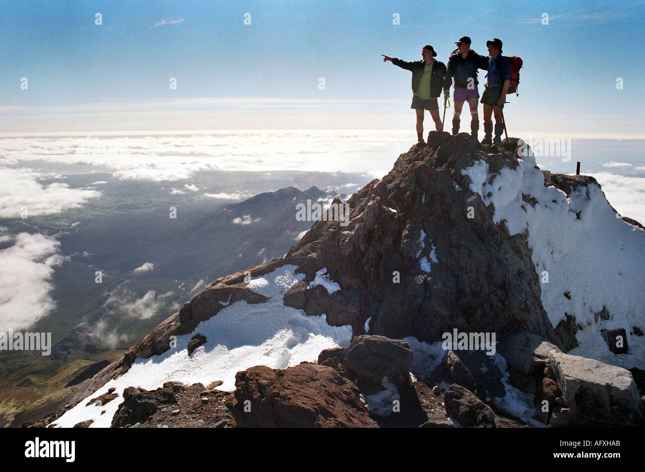 Three climbers standing on top of Mount Egmont  or Mt Taranaki New Zealand Stock Photo
