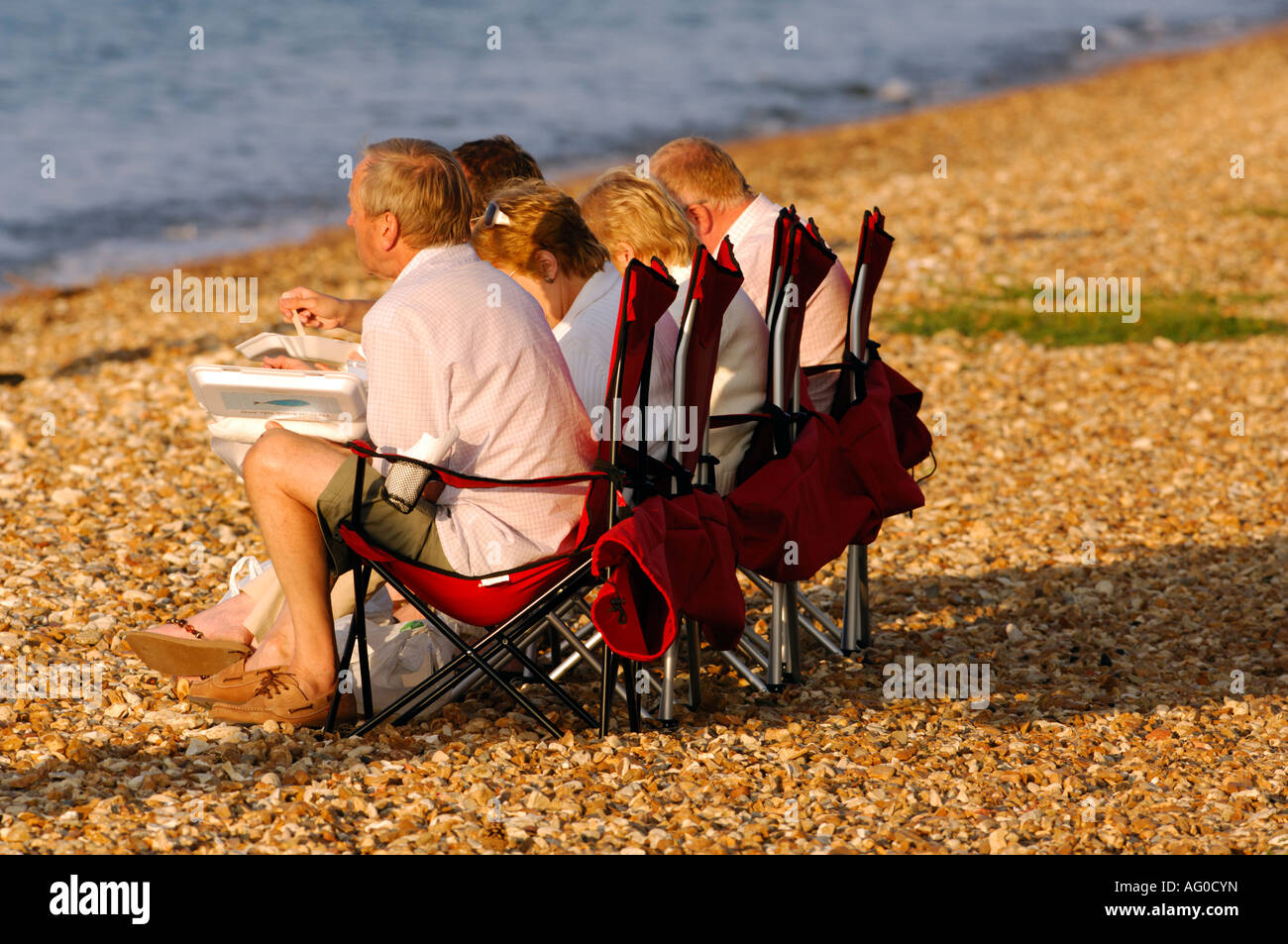 4 four middle aged ladies and gentlemen watching the racing during cowes week regatta on the isle of wight on the beach seaside Stock Photo