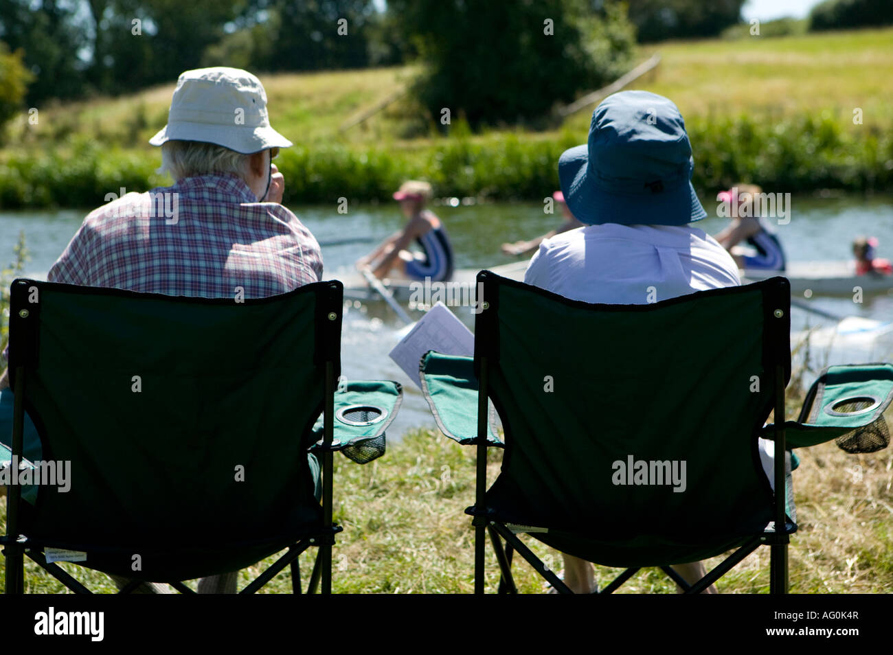 Middle Aged Couple Sitting In Camping Chairs Watching Rowing
