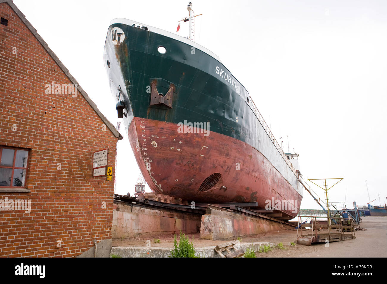 Skurin at Dry Dock A large old ocean freighter its bow thrusters and anchors showing pulled up in drydock Stock Photo
