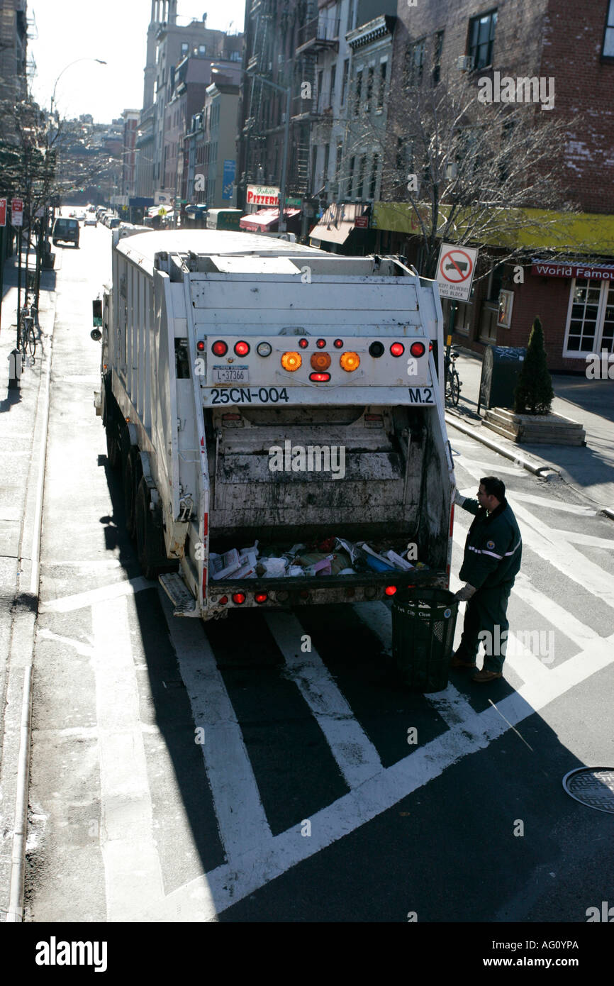 city refuse worker checks the back of a garbage truck on a cross walk bleeker st Stock Photo