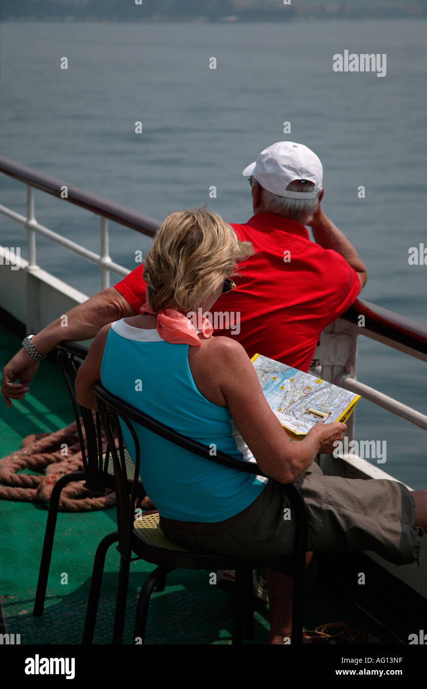 Older man and woman tourists on board a ferry, Lake Garda, Italy, Europe, with woman looking at map of area Stock Photo