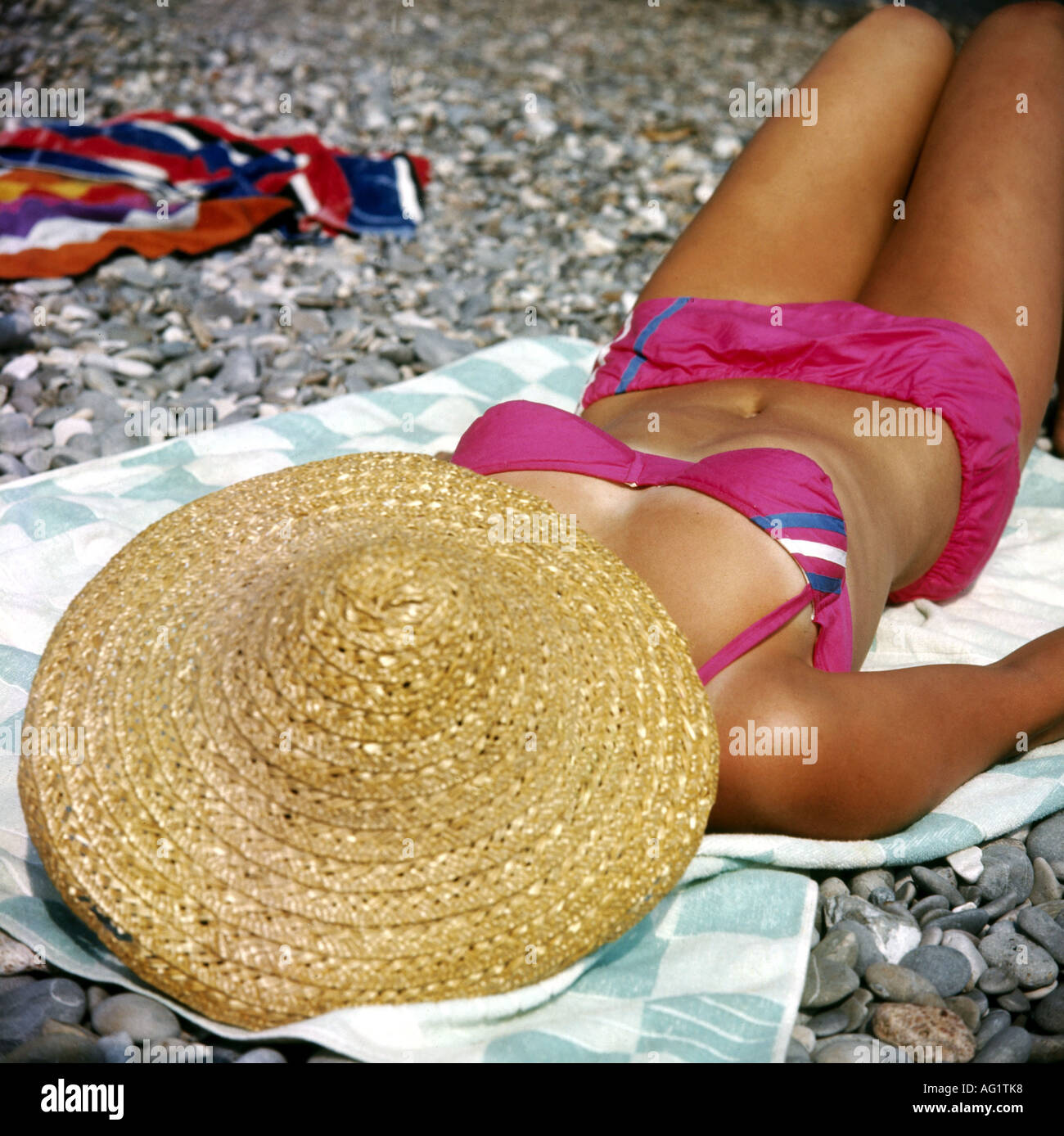 people, woman, half length, wearing bikini, 1980s, 80s, towel, straw hat, accessory, sun shade, two piece, tanning, sunbathing, Stock Photo