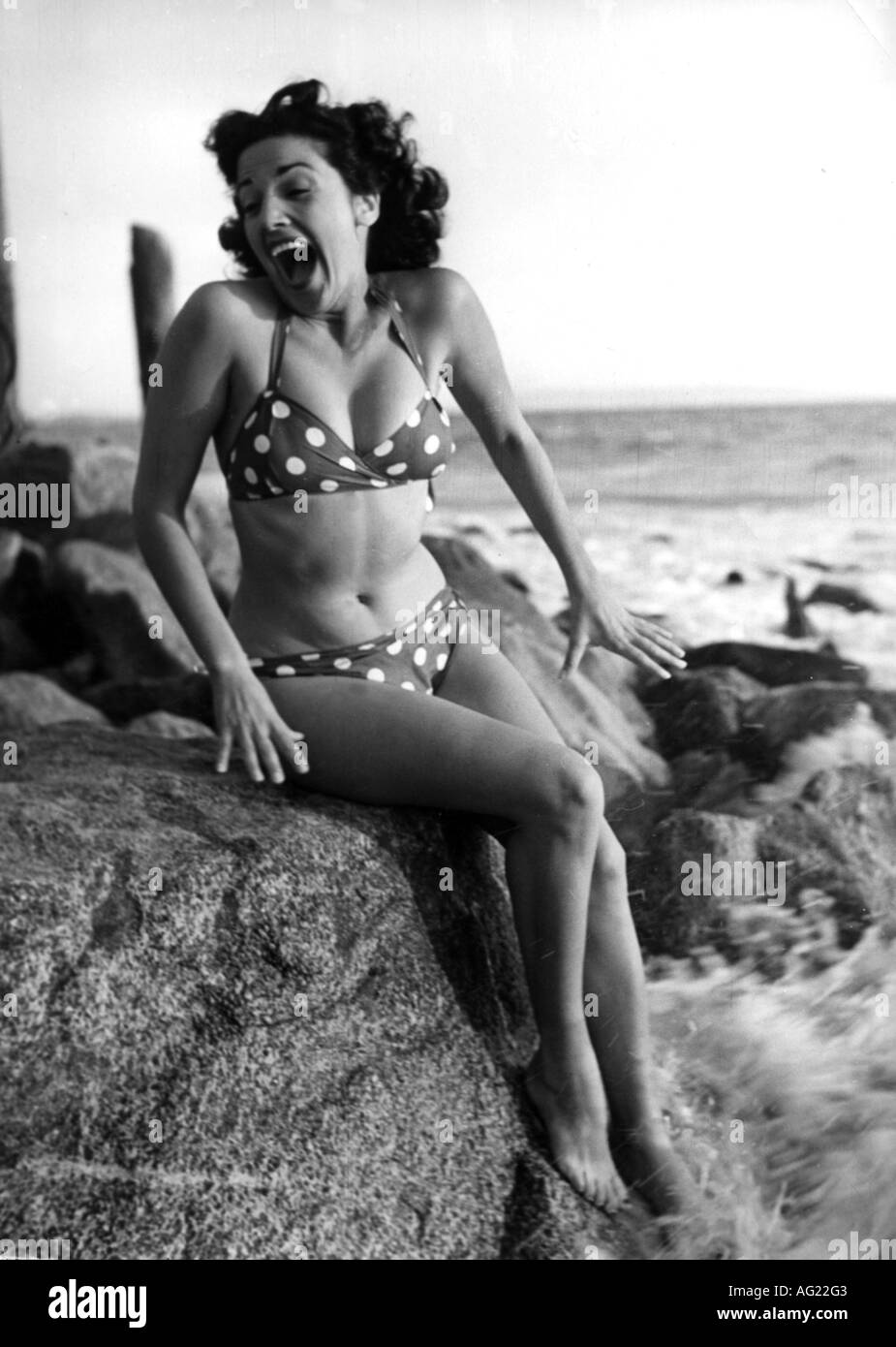 fashion, woman, sitting, full length, wearing bikini, 1950s, 50s, historic,  historical, swimsuit, bathing suit, clothing, two-piece, spotted, cooling,  refreshment, spray, sea, seaside, surf, water, mouth, opened, open,  shouting, 20th century, people ...