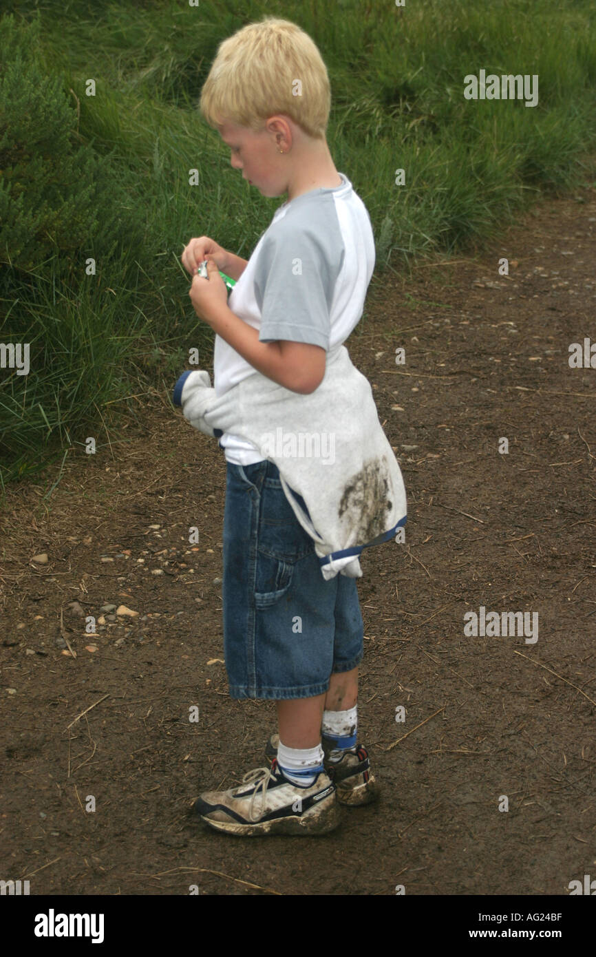 7 year old boy standing with muddy shoes and clothes Stock Photo