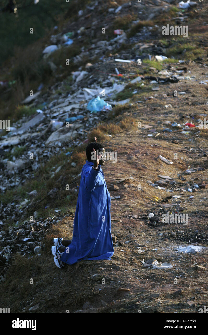 A man prays next to a dump site on a Yeoville hill overlooking Johannesburg, South Africa. Stock Photo