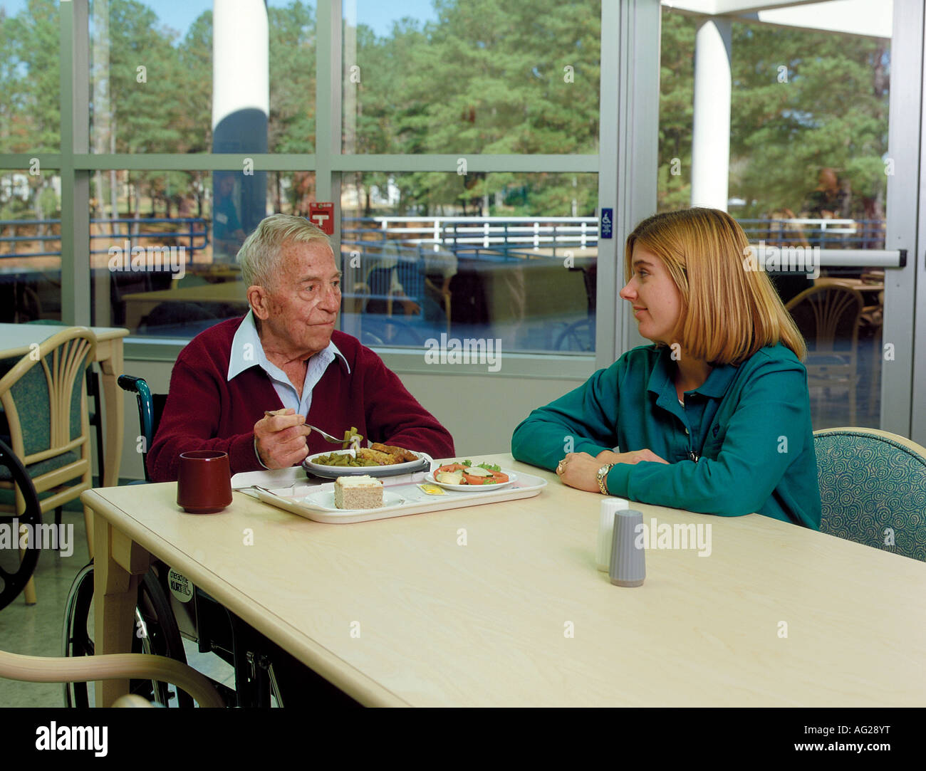 Elderly man with a disability having lunch with one of his therapists Stock Photo