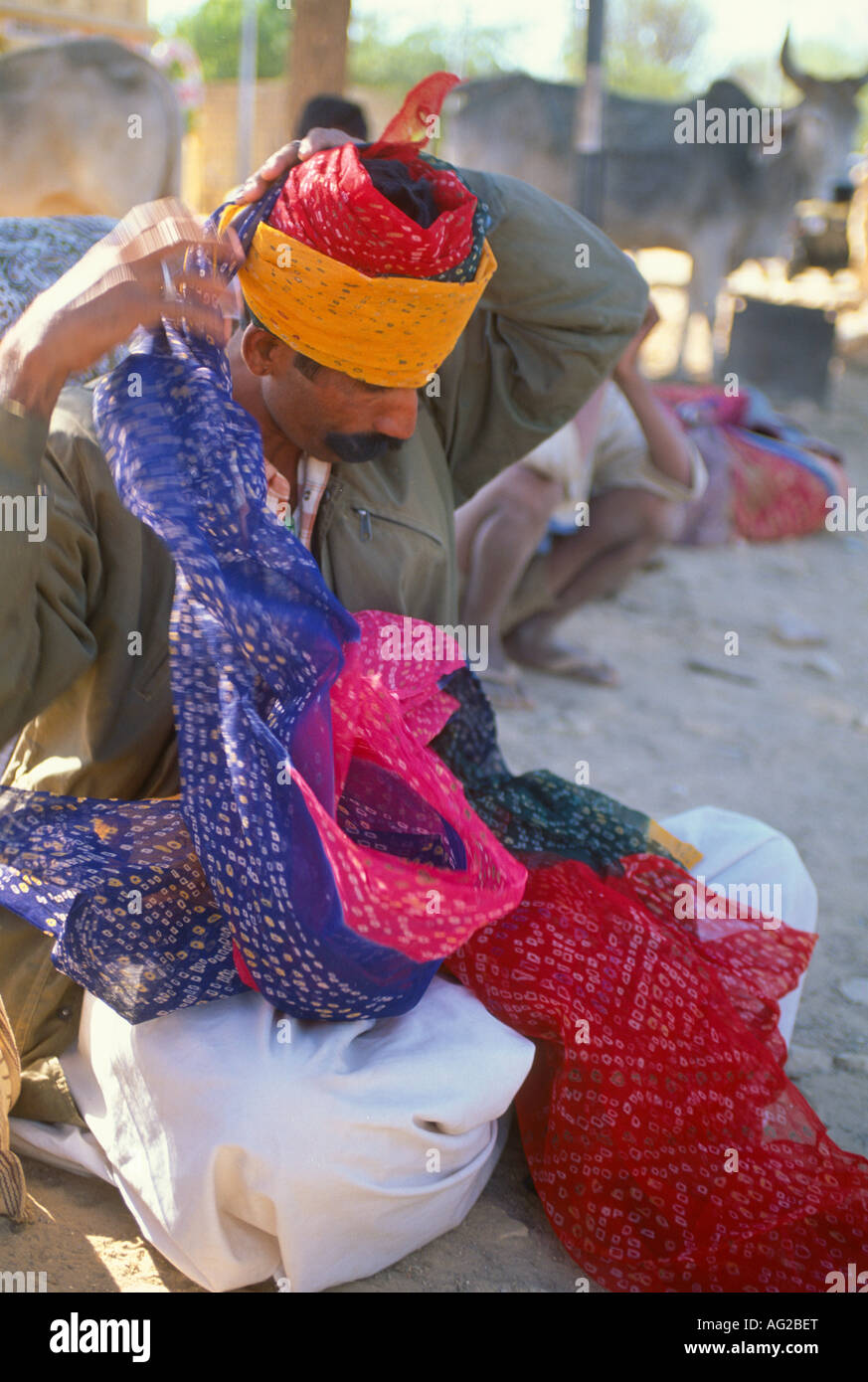 Man tying a brightly coloured turban on the street, Jaisalmer, Rajasthan, India Stock Photo