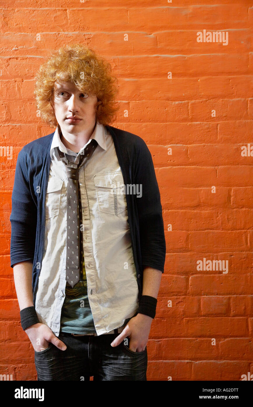 Young man standing in front of brick wall Stock Photo - Alamy