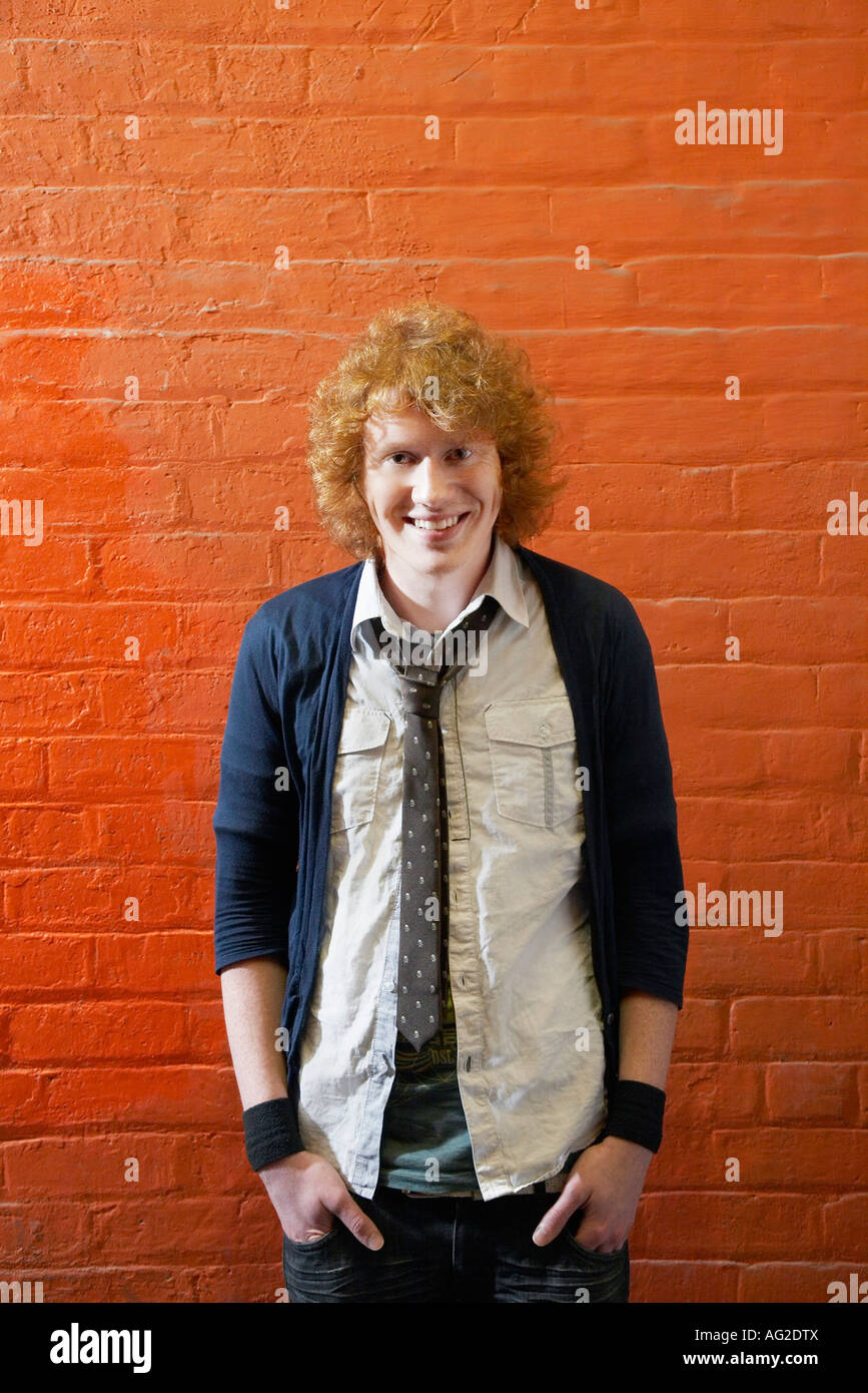 Smiling young man standing in front of brick wall Stock Photo - Alamy